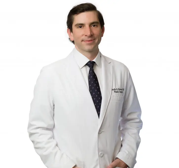 Male doctor in a white coat and dark tie, smiling at the camera.